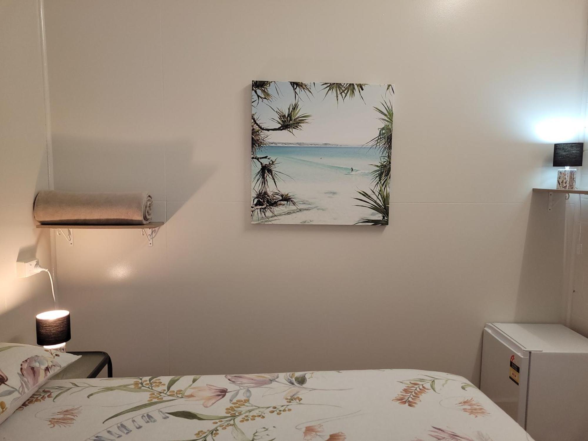 Travellers Paradise Cairns Eksteriør bilde A photograph of a bedroom with a bed, a nightstand, a lamp, a painting, and a television